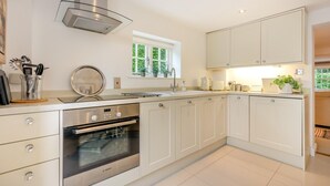 A modern kitchen with white cabinetry, a Bosch oven, a stainless steel range hood, and a window with a view of greenery. - 2 Bed in Matfield (oc-s42710) (Matfield)