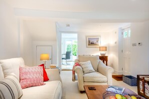A living room with a sofa, armchair, coffee table, and a dining area with a table and chairs.