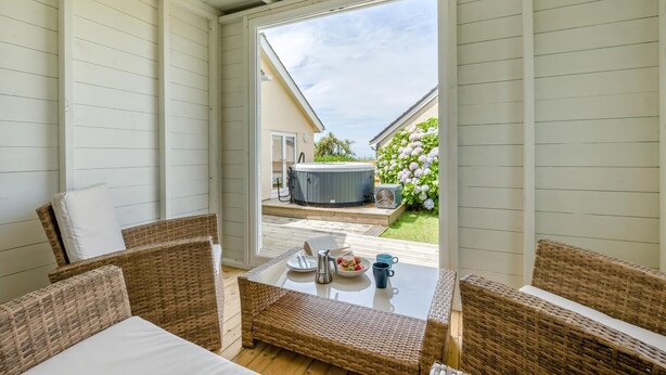Un balcon agrémenté de meubles en osier, un jacuzzi et un jardin où poussent des hortensias.