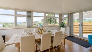 Un coin repas avec une table dressée pour quatre personnes, de grandes fenêtres et une vue sur l’extérieur.