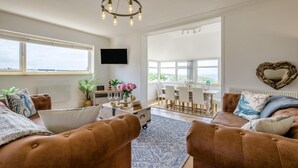 Un salon spacieux doté d’une grande fenêtre, d’un lustre et offrant une vue sur l’extérieur.
