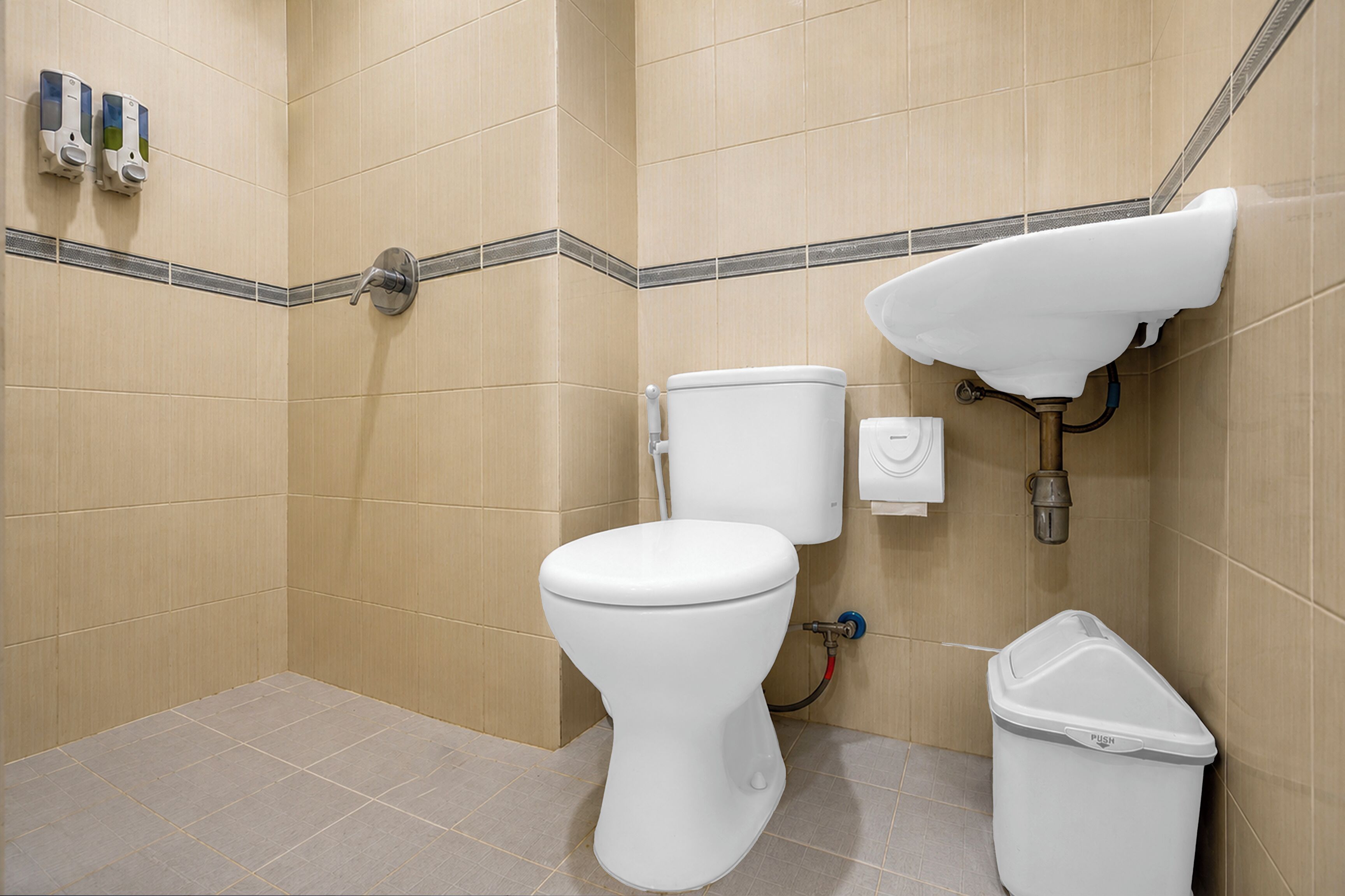 Un baño con inodoro, lavamanos y un cubo de basura.