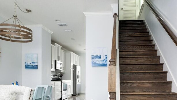 Una escalera con escalones y barandilla de madera que conduce a una habitación con paredes y techo blancos.