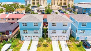 Zona residencial con dos casas azules, un estacionamiento y una vista de un hotel al fondo.