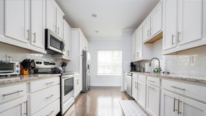 Una cocina moderna con armarios blancos, electrodomésticos de acero inoxidable y piso de madera.
