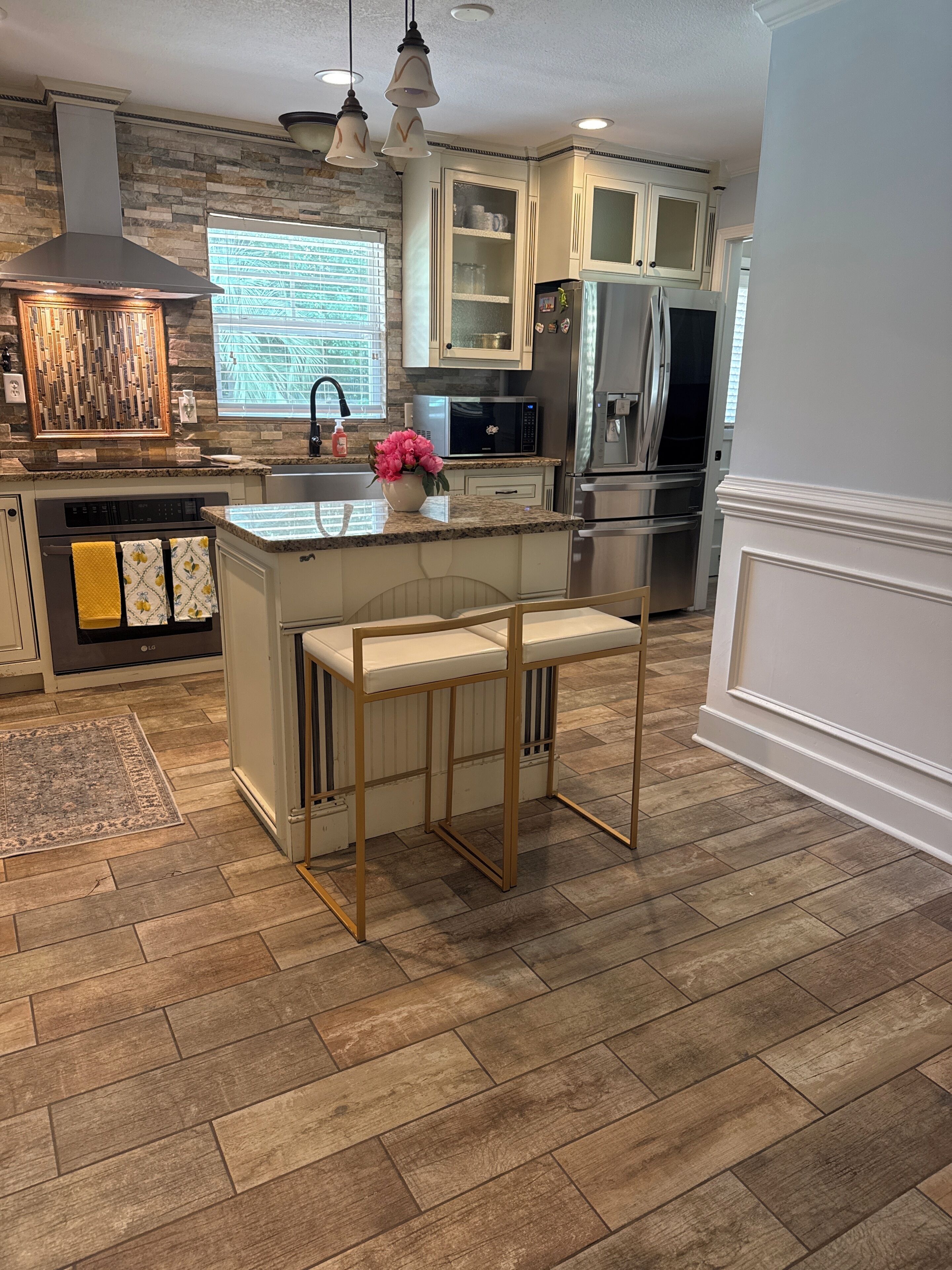 A modern kitchen with granite countertops, stainless steel appliances, and a central island with bar stools.