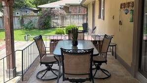 Un patio techado con una mesa y sillas, una planta en maceta y un farol colgante.