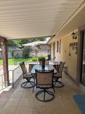 A covered patio with a table and chairs, a potted plant, and a hanging lantern. - 3-bedroom house in serene Warner Robins with cool AC and a pool. (Warner Robins)