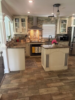 A kitchen with granite countertops, a central island, a built-in oven, and a stone backsplash. - 3-bedroom house in serene Warner Robins with cool AC and a pool. (Warner Robins)