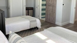 A bedroom with two beds, a wardrobe, and a door leading to a bathroom. - Vacay or Relocation Home | 3 min walk to beach (Neptune Beach)