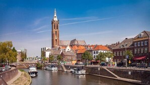 Un canal con barcos, una torre destacada y edificios históricos a orillas del agua.