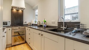 Una cucina moderna con forno a incasso, forno a microonde, lavello e una finestra che lascia entrare luce naturale.
