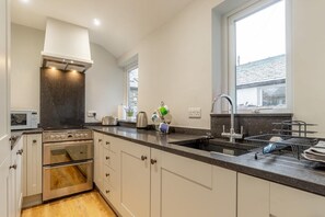 Eine moderne Küche mit integriertem Backofen, Mikrowelle, Spüle und einem Fenster für natürliches Licht.