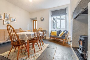 Ein gemütliches Wohnzimmer mit Kamin, eine Essecke mit Holzkreisläufen und einem Tisch, und ein Fenster mit Blick.