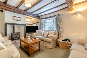 A cozy living room with a fireplace, sofa, coffee table, and a television. - 4 Bed in Bassenthwaite (oc-m40272) (Wythop)