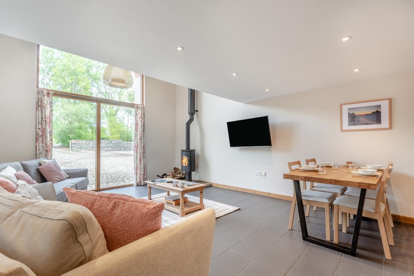 A modern living room with a sofa, coffee table, and a dining area with chairs and a table.