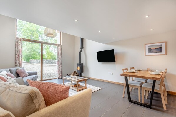 A modern living room with a sofa, coffee table, and a dining area with chairs and a table. - 2 Bed in Bassenthwaite (oc-b40273) (Wythop)