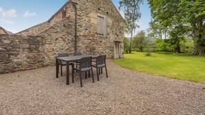 En bygning i sten med en grusbelagt terrasse og udendørs siddepladser.