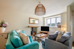 Un salon chaleureux avec une cheminée, un téléviseur et des fauteuils confortables.