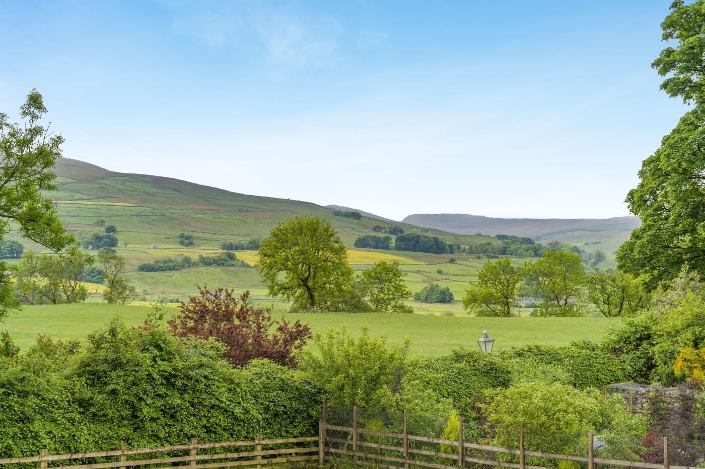 A rural landscape with rolling hills, a wooden fence, and a lamp post.