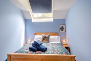 A bedroom with a skylight, a bed with floral bedding, a pillow with a floral pattern, and a framed picture on the wall. - 3 Bed in Coldstream (oc-c39085) (Coldstream)