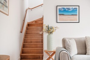 A wooden staircase, a framed landscape picture, and a vase with flowers on a small table. - 4 Bed in Trebetherick (oc-l50183) (La Mohay)