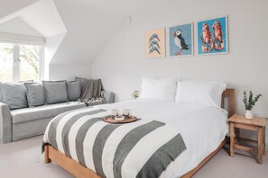 A bedroom with a bed, a sofa, a bedside table, and three wall-mounted paintings. - 4 Bed in Trebetherick (oc-l50183) (La Mohay)