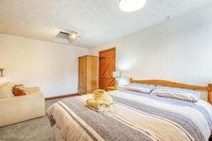 Un dormitorio con una cama, un armario de madera, una mesita de noche con lámpara y un ventilador de techo.