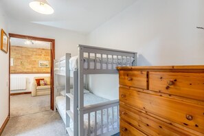 A room with bunk beds, a wooden dresser, a radiator, and a brick wall. - 2 Bed in Thurleigh (oc-s42690) (Thurleigh)