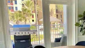 Una habitación con puerta corrediza de vidrio que da a un espacio exterior con una parrilla y sillas.