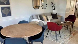 Una sala de estar con un sofá, dos sillones, una mesa redonda y una butaca roja.