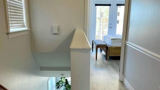 Un pasillo con piso de madera, un banco y una planta en maceta.