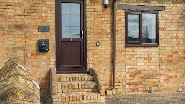 A brick house with a dark brown door, a small window, and a mailbox. - 2 Bed in Thurleigh (oc-o42689) (Thurleigh)
