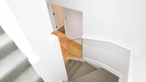 Un interior moderno con una escalera, suelo de madera y paredes blancas.