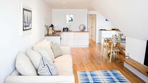 Una sala moderna con un sofá, una mesa de centro y un comedor con una mesa y sillas.