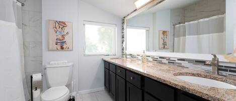 Un baño moderno con inodoro, lavamanos y un espejo grande.