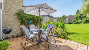 An outdoor patio with a table and chairs, a barbecue grill, and a large umbrella. - 2 Bed in Goldenbank (oc-t42750) (Goldenbank)