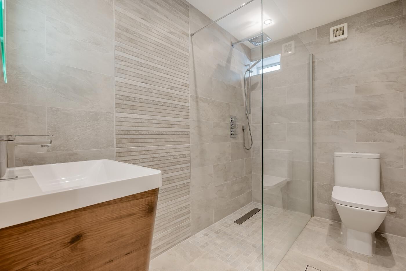 Une salle de bain moderne avec une douche à parois de verre, un meuble-lavabo en bois et des toilettes blanches.
