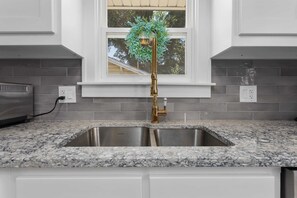 A kitchen with a granite countertop, stainless steel sink, and a brass faucet. - Single Level Ranch - 2 Bedroom Home - sleeps 4 (North Kansas City)