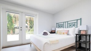 Ein Schlafzimmer mit Bett, Nachttisch, Kommode und einer Glastür zum Balkon.