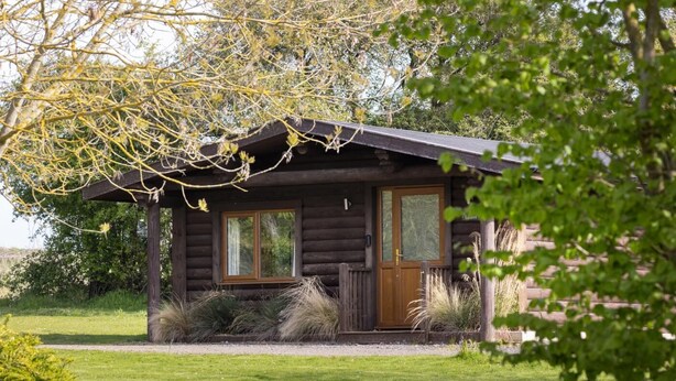 Eine Holzhütte mit Haustür, Fenstern und einer kleinen Veranda.