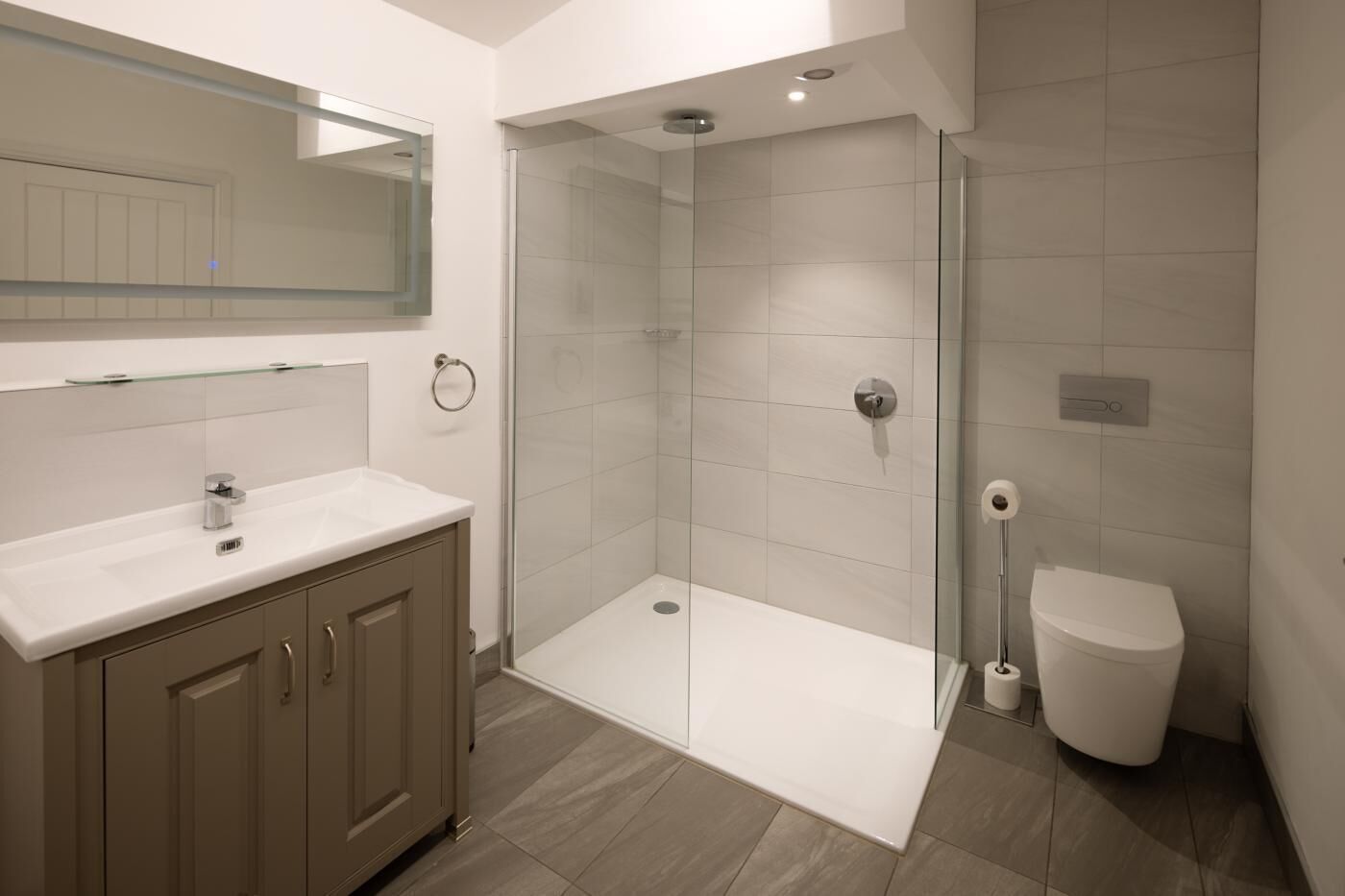 Une salle de bain moderne avec une douche à parois de verre, un lavabo blanc et des toilettes.