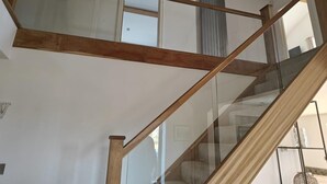 Una scala con ringhiere in legno e pannelli di vetro che conduce a un piano superiore.