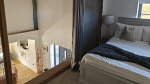Una camera da letto con un letto, una finestra, una lampada e vista su un balcone.