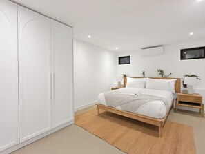 Ein modernes Schlafzimmer mit Bett, Nachttischen, einem Kleiderschrank und einem Fernseher.