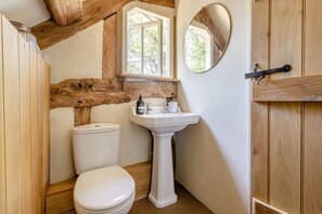 Ein Badezimmer mit Holzbalkendecke, einem Fenster, einem Waschbecken und einer Toilette.