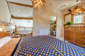 Ein Schlafzimmer mit Bett, Schminktisch, Fenster und einem durchgegangenen Tür angedeuteten Badezimmer.