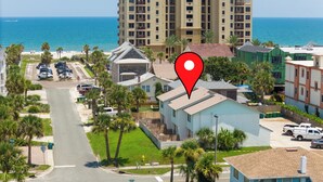 Zona residencial con vista a la playa, estacionamiento y un edificio destacado con un marcador rojo de ubicación.