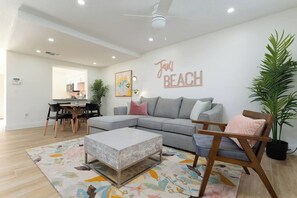 Ein Wohnzimmer mit einem grauen Sofa, einem Holztisch und einem farbenfrohen Teppich.
