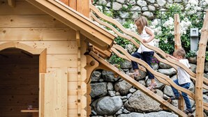 Children climbing wooden stairs with a stone wall and wooden fence in the background. - Cozy vacation rental with a spacious loggia and a magnificent view (Trentino-Alto Adige)